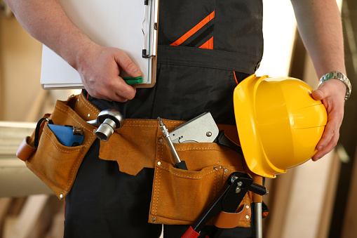 Cropped professional builder holding construction tools and helmet. Construction or architecture work concept. Safe construction and renovation.