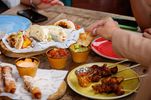 istock Holding tortilla chip and dipping into vegetable sauce at restaurant table 1364356656