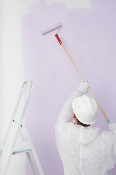 istock a worker in a helmet paints the wall purple 1364356908