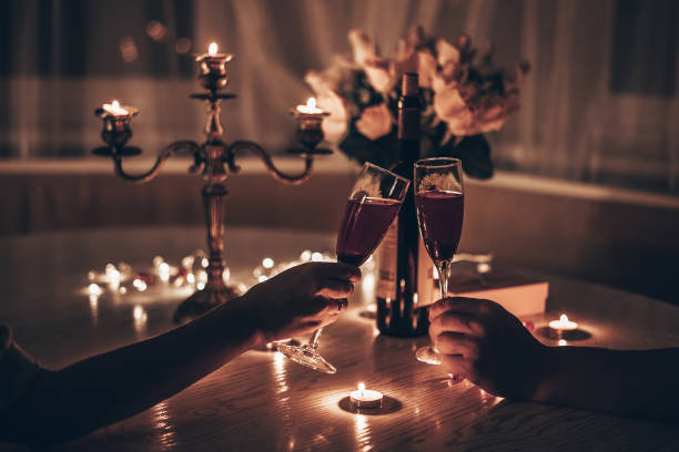 hände mann und frau halten gläser wein und genießen romantisches candle-light-dinner am tisch zu hause. hände mann und frau halten ein glas wein. konzept des valentinstags oder candlelight-dates in der nacht. - food and drink holidays and celebrations people valentines day stock-fotos und bilder