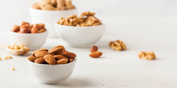 istock Almonds and other nuts in white bowls on a white background. Banner 1364359805