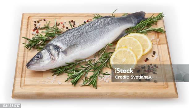 Fresh Uncooked Seabass With Lemon And Rosemary On Wooden Board Over White Backdground With Clipping Path Stock Photo - Download Image Now