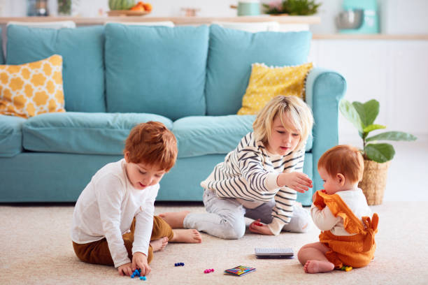 niños lindos, hermanos jugando en casa, el hermano mayor no deja que la hermana coma partículas pequeñas de juguete, peligro de asfixia - living dangerous fotografías e imágenes de stock