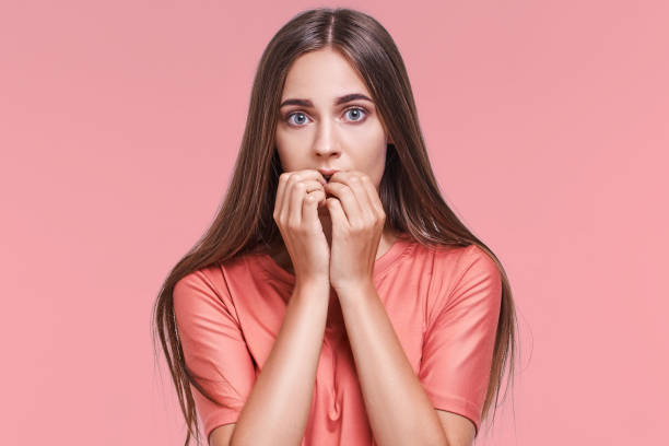 istock Frightened young caucasian woman with eyes wide open biting nails 1364361913