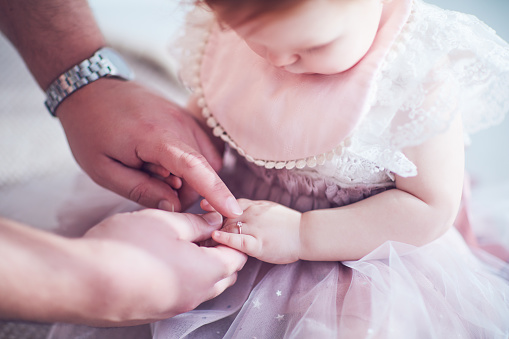 daddy puts on cute golden finger ring on daughter's little hand