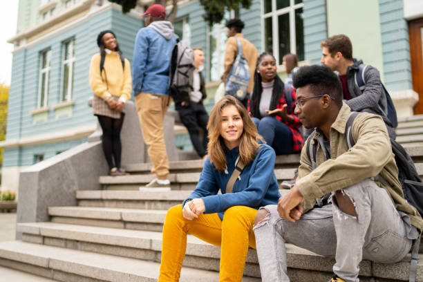 Student friends sitting together and having a conversation Group of happy young friends sitting in college campus and talking. multi ethnic group college student group of people global communications stock pictures, royalty-free photos & images