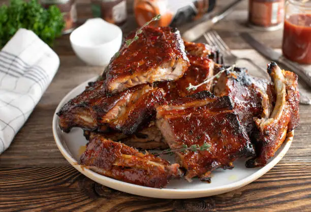 Delicious traditional pork ribs with honey and barbecue sauce. Served with cross section view on wooden an rustic table background. Ready to eat
