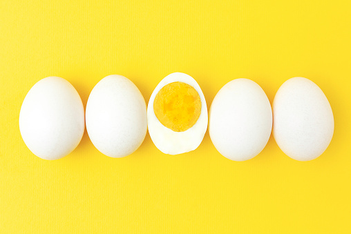 Creative photos of a boiled chicken egg on a yellow background