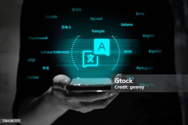 A Person Is Holding A Smartphone With A Holographic Projection Of The Translator Application Symbol Stock Photo - Download Image Now
