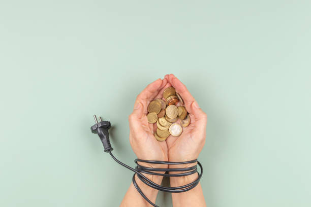 female hands tied up with electric power cable cord holding euro coins. energy efficiency, power consumption, rising electricity price and expensive energy concept - electric plug electricity power cable imagens e fotografias de stock