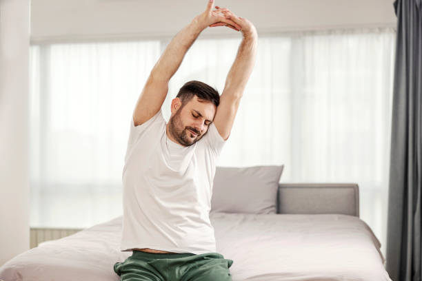 istock A morning man stretching and waking up in his cozy bedroom. 1364368621