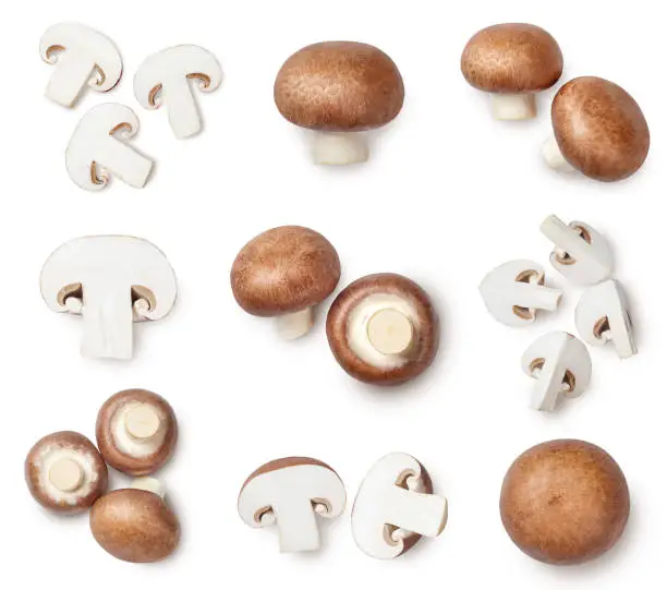 Whole and sliced champignons isolated on white background. Top view.