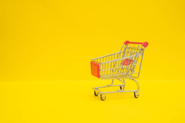 istock Small steel shopping trolley on yellow surface 1364368641