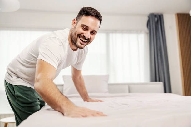 A tidy morning man making his bed in the morning at his cozy home. stock photo