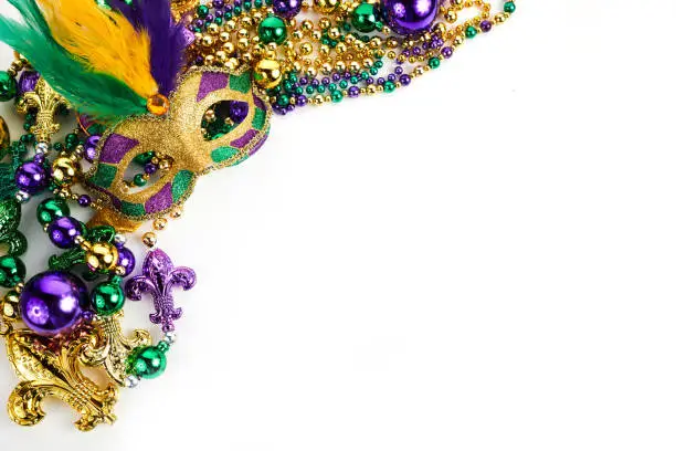 Photo of Frame of Mardi Gras mask and beads isolated on white background.