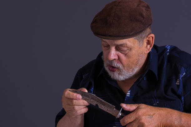 Bearded Caucasian senior man holding and examining rusty knife