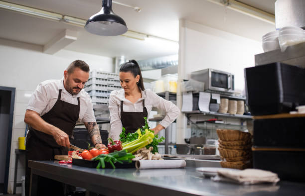 istock Chef teaching how to cook, cutting vegetables indoors in commercial kitchen. 1364372149