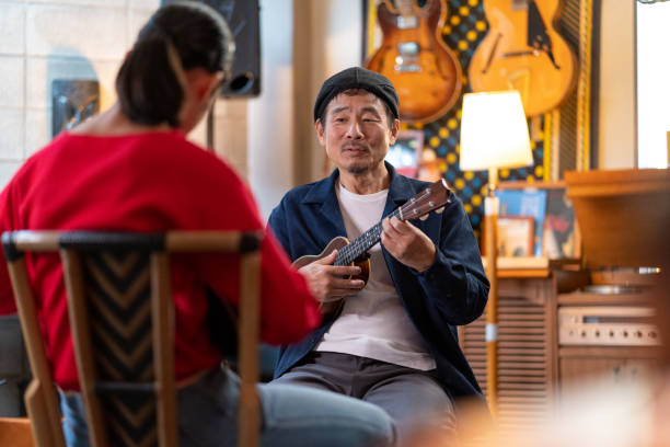istock Senior male teaching a pre-adolescent student how to play the ukulele 1364372179