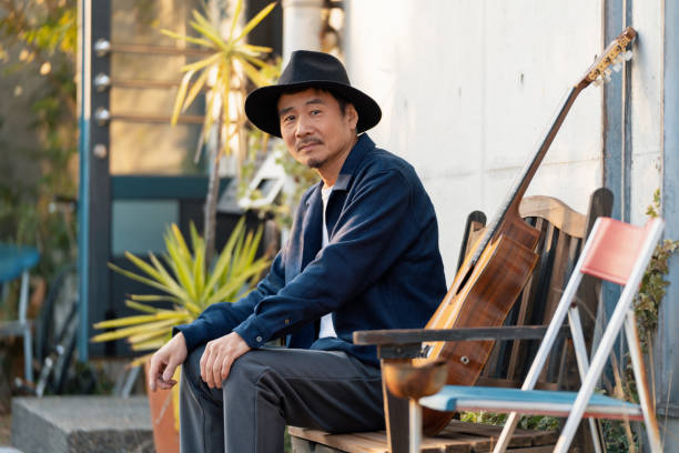 istock Stylish mature Japanese man sat outside with a guitar 1364372481
