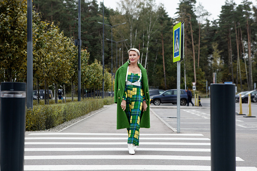Stylish woman in a warm wool green coat. Style and fashion. Street fashion trend look. Fashionable adult model walks down street