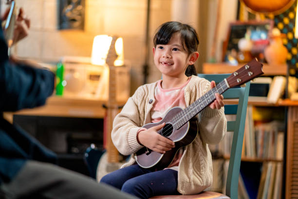 młoda dziewczyna ucząca się grać na ukulele - guitar child music learning zdjęcia i obrazy z banku zdjęć