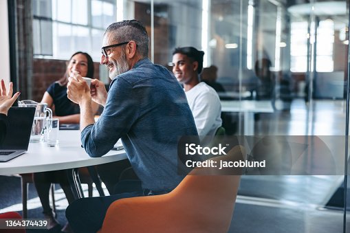 istock Happy mature businessman attending a meeting with his team 1364374439
