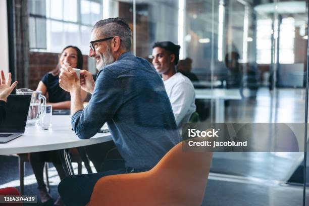 Happy Mature Businessman Attending A Meeting With His Team Stock Photo - Download Image Now
