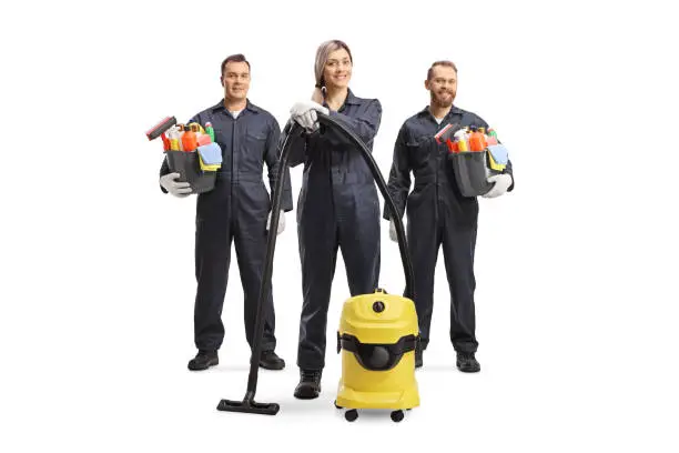 Photo of Team of professional cleaners in uniforms with a vacuum cleaner and cleaning supplies