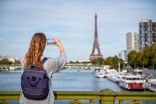 tourist taking photo of Eiffel tower in Paris with a smartphone, travel in Europe