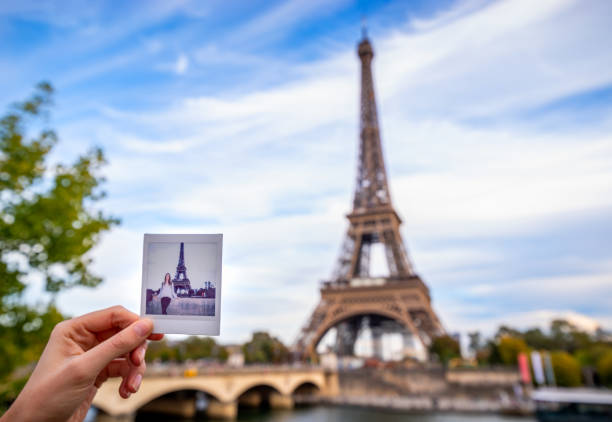 hand with an instant photo of a woman in front of the Eiffel Tower in Paris, France