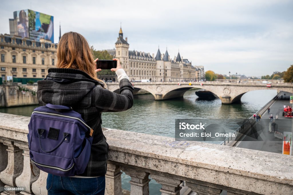 tourist woman taking photo in Paris tourist woman taking photo of Seine River in Paris with a smartphone, travel in Europe Paris - France Stock Photo
