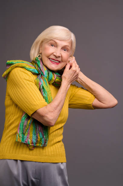 istock Blone smiling senior woman putting on long earrings 1364383142