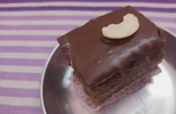 Photo of chocolate cake pastry with cashew on top.