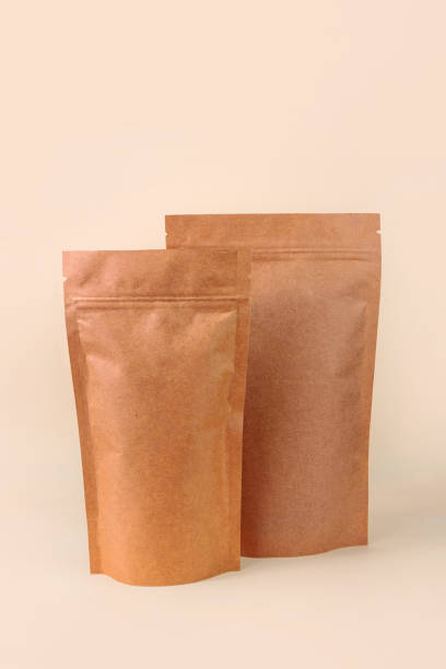 istock Pouch bags mockup neutral beige background monochrome. Merchandise packaging. Blank brown kraft paper pack demonstration 1364385846