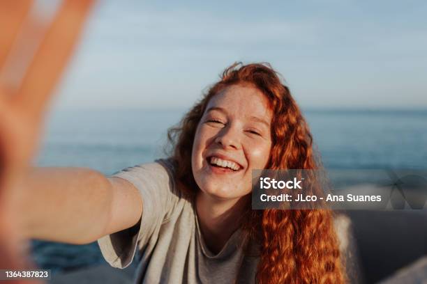 Cheerful Young Woman Taking A Selfie Next To The Sea Stock Photo - Download Image Now