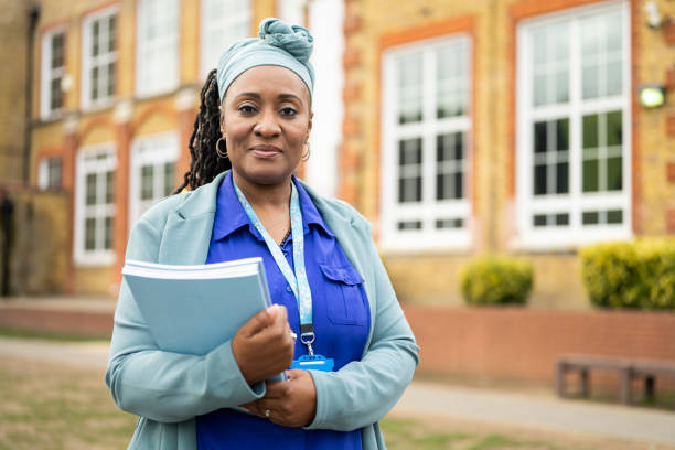 istock Black female educator standing outdoors with exam booklets 1364388468