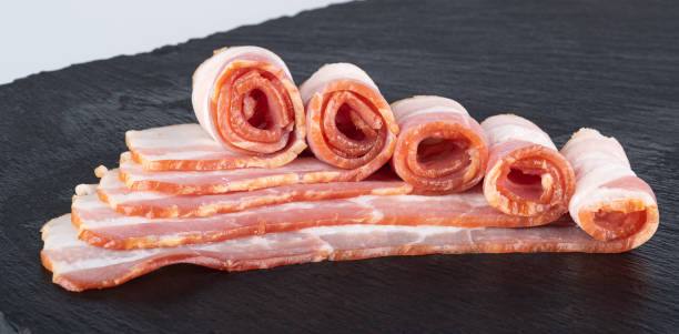 istock Rolls of fresh bacon on a black cutting board 1364389097