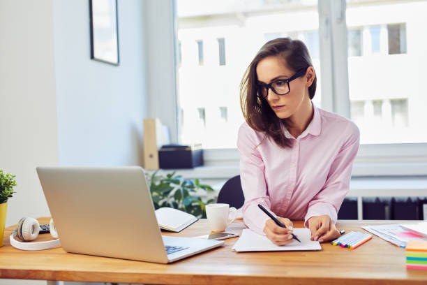 istock Busy oung woman working in office with documents and laptop 1364391186