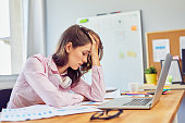 Tired young woman in office having headache working on project