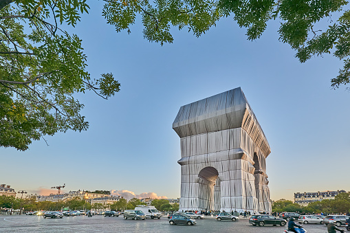 Paris, France - September 29, 2021: Traffic at the Arc de Triomphe in Paris in the evening. The triumphal arch is covered as part of an art project by Christo and his wife Jeanne-Claude.