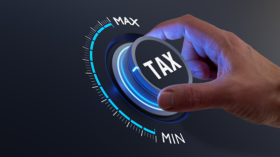 Tax reduction and deduction for businesses and individuals. Concept with hand turning knob to low taxation rate. Return form, exemptions, incentives.