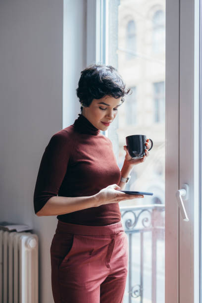 A Beautiful Businesswoman Drinking Her Morning Coffee And Reading E-mails Using Her Smartphone