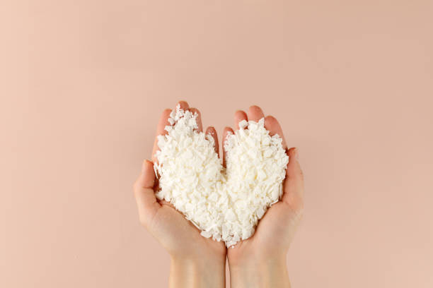 Hand with organic white Soy wax flakes for candles and sachet. Heart. Flatlay, top view. Natural soy and coconut wax for candlemaker. Hand with organic white Soy wax flakes for candles and sachet. Heart. Flatlay, top view. Natural soy and coconut wax for candlemaker. candle wax stock pictures, royalty-free photos & images
