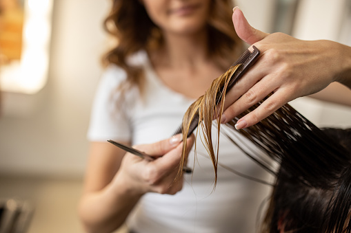 Close up of unrecognizable female hairdresser, cutting her client hair