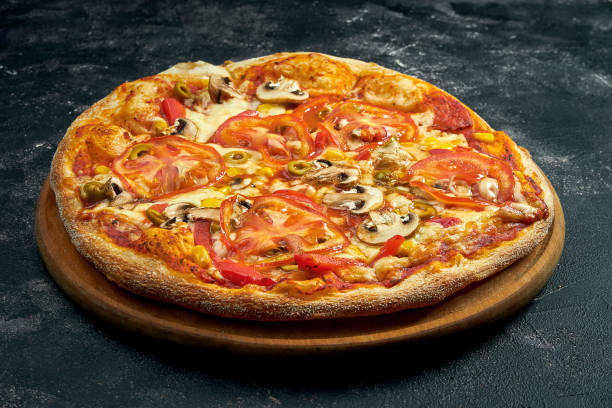 istock Pizza with tomatoes, olives and mushrooms on a black stone background. 45 degree angle view. Close-up, selective focus 1364395406