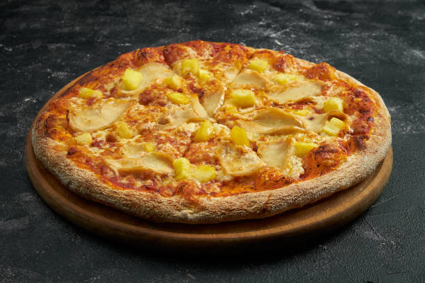 istock Pizza with chicken and pineapple on a black stone background. 45 degree angle view. Close-up, selective focus 1364395435