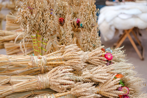 Many symbolic sheaves of wheat with flower decorations - Didukh as a Ukrainian Christmas symbol on souvenir market - sheaf of wheat used for celebrating Christmas in Ukraine, ancient pagan traditions