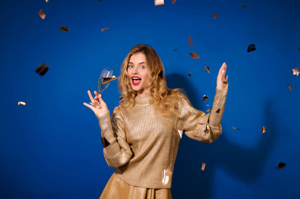 istock Girl with champagne looking at camera and falling confetti 1364397070
