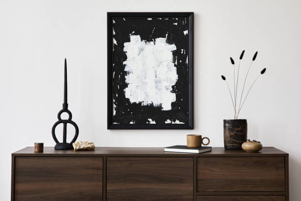 istock Stylish living room interior composition with mock up poster frame, brown wooden commode, candlestick and small home decorations. White wall. Copy space. Template. 