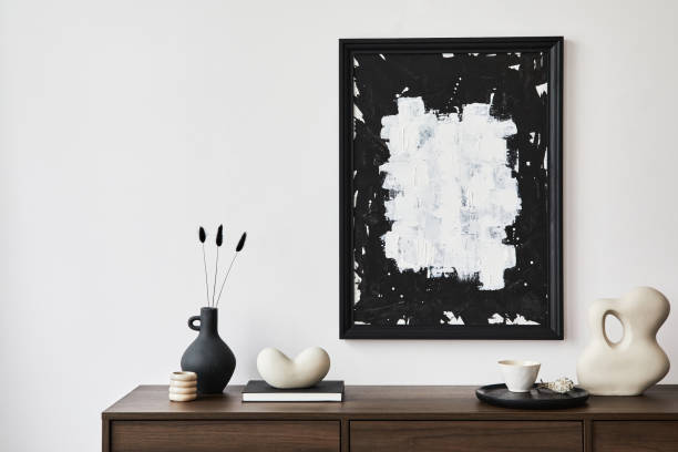 istock Minimalistic composition of creative living room interior with mock up poster frame and stylish small personal accessories on wooden commode. Copy space. Template. Real photo.